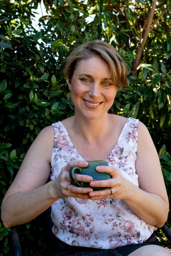 Friendly home cook holding a mug in a garden setting, representing Flexible Family Kitchen