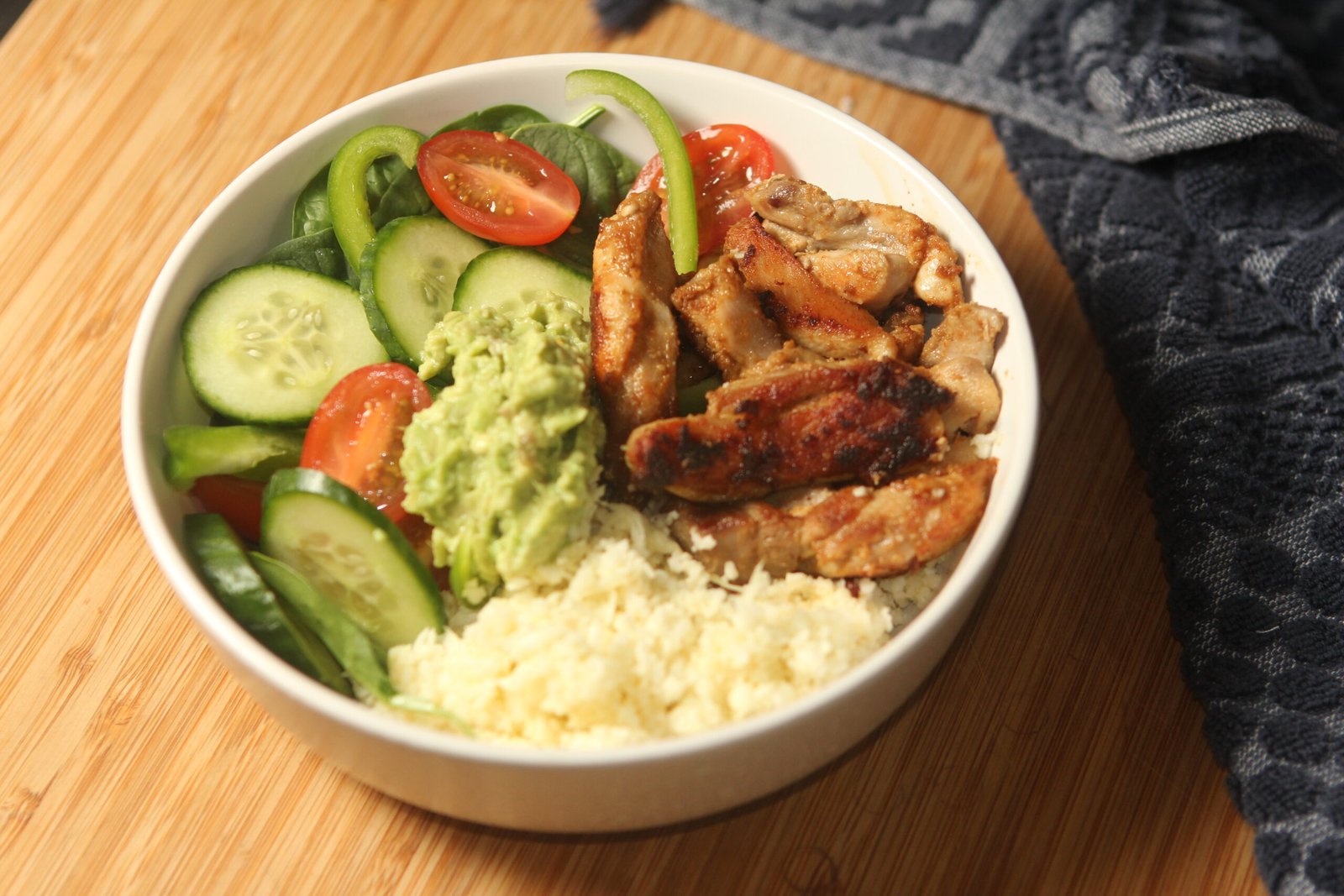 Chicken taco bowl recipe with spiced chicken, rice, avocado, and fresh salad vegetables in a family-style bowl meal.