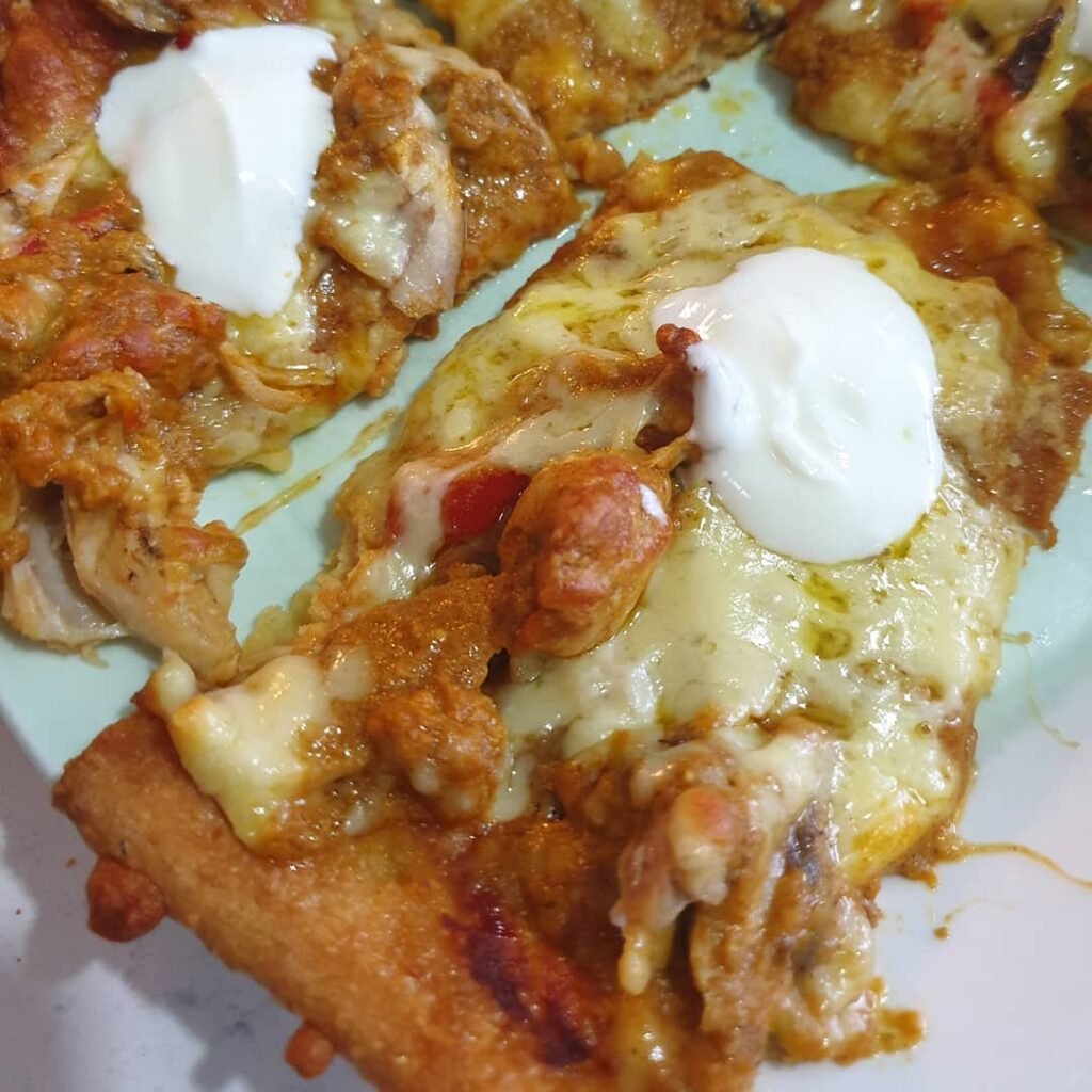 Satay chicken pizza topped with yoghurt served as part of a mixed dietary needs family pizza night idea
