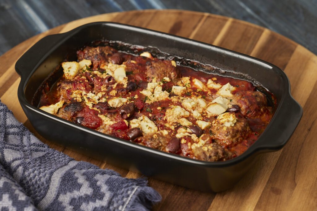 Greek meatball bake with feta, olives and tomato sauce in a baking dish