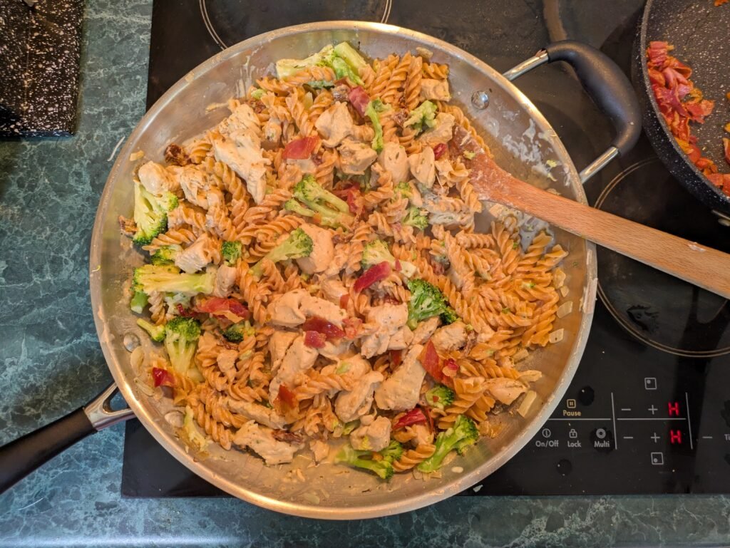 Pantry dinner creamy chicken pasta with sun-dried tomatoes, sour cream, Parmesan, broccoli and crispy prosciutto.